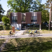 Das Naturpark-Haus mit seiner modernen Glasfassade ist von Radfahrern auf einer Allee umgeben.