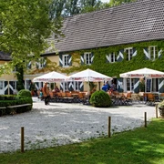 Gastronomie der Wasserburg Haus Graven in Langenfeld Sonniger Außenbereich der Wasserburg Haus Graven mit einladenden Sitzgelegenheiten und üppiger Begrünung.
