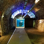Zeittunnel Wülfrath Beleuchteter Tunnel mit gewölbtem Steinhaus und einem leuchtenden Plakat mit einem Schädelmotiv.
