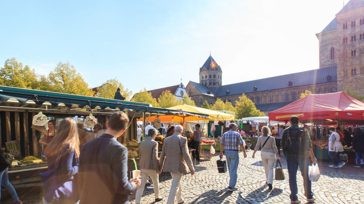 Verschillende kraampjes op de weekmarkt in Osnabrück met daarachter de herfstige bomen