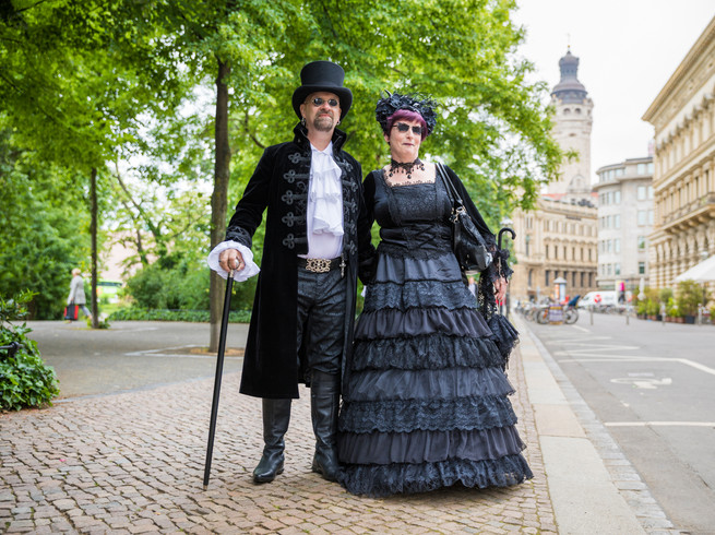 Zwei in aufwändigen schwarzen Kostümen gekleidete Menschen besuchen das Wave-Gotik-Treffen in Leipzig, im Hintergrund das Neue Rathaus, Veranstaltungen, Musik, Kultur, Szene