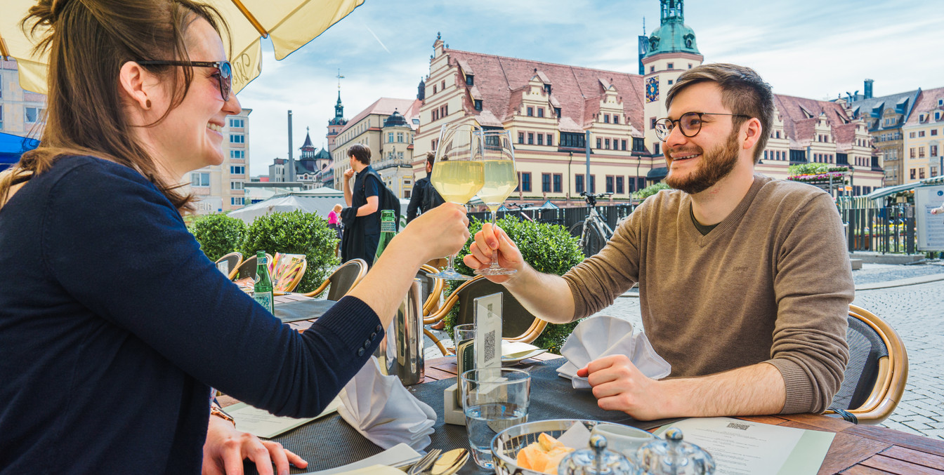 Ein junges Paar sitzt auf dem Freisitz des Restaurants Weinstock am Markt Leipzig und genießt gute Küche und leckeren Wein, Freizeit, Gastronomie, Kulinarik