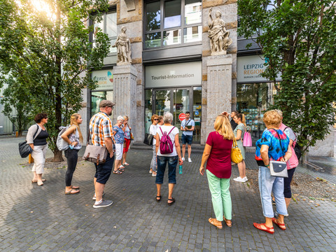 Eine Gruppe Touristen steht vor dem Eingang der Tourist-Information Leipzig, Ausflug, Kurzurlaub