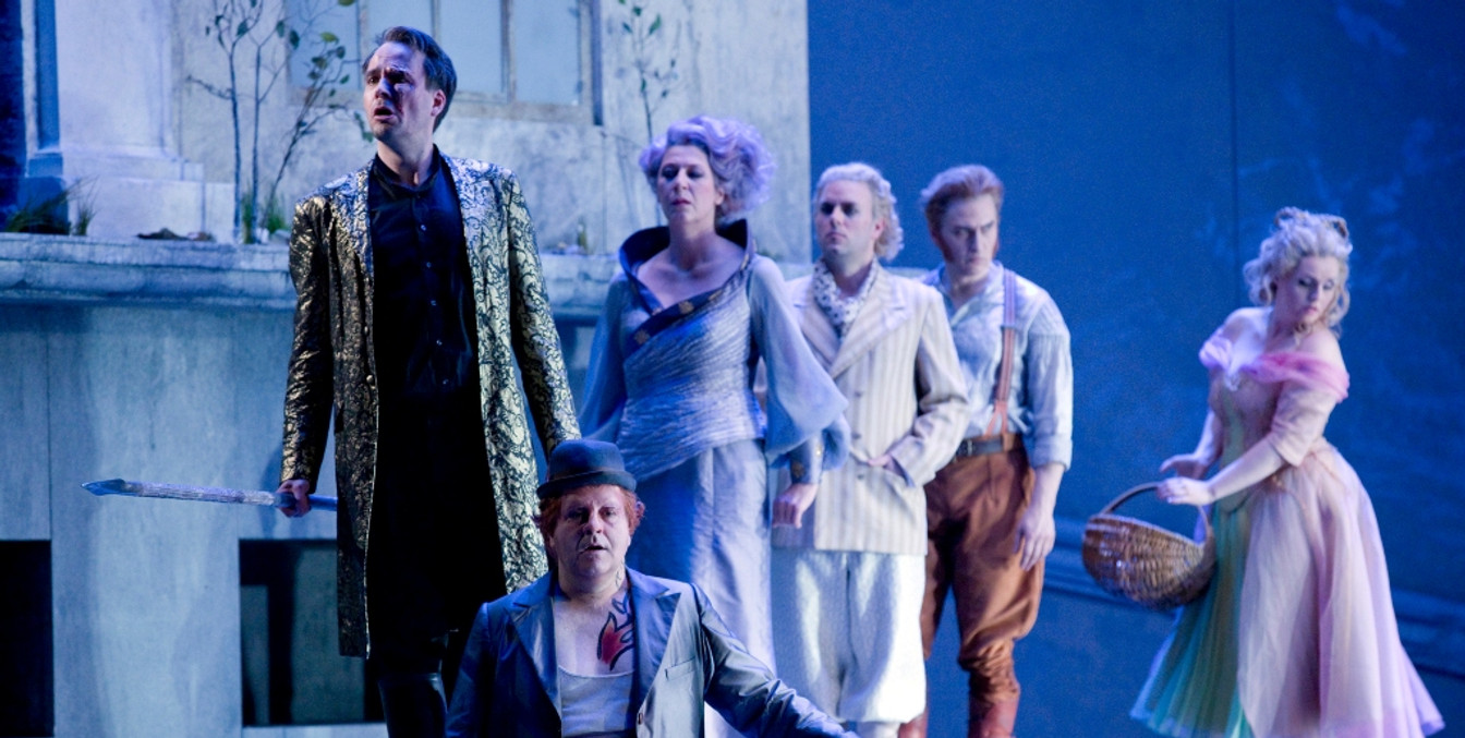 Sechs verkleidete Schauspieler:innen stehen auf einer in blau getauchten Bühne, Oper in Leipzig, Kultur