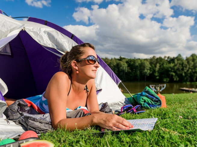 Eine Frau liegt in einem Zelt und ließt eine Broschüre, Camping in Leipzig, Urlaub