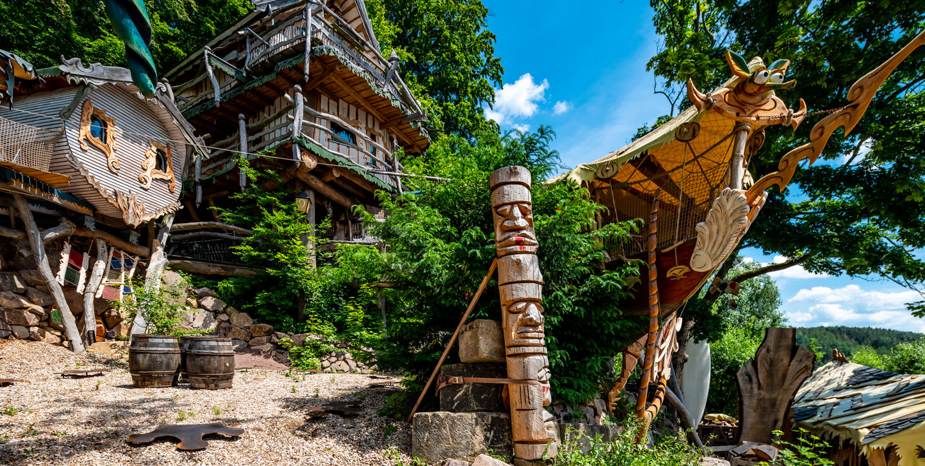 individuell gestaltete Baumhäuser stehen an einem Hang, Urlaub in Leipzig Region, Camping