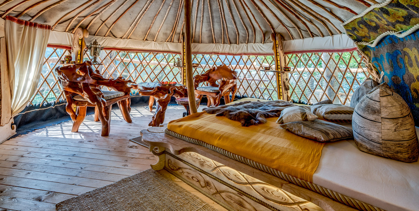 In einem Baumhaus steht ein Bett, Tisch und Stühle, welche jeweils mit Holzschnitzerein verziert sind, Urlaub in Leipzig Region, Familie.
