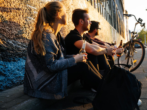 Drei jugendliche sitzen vor dem Westwerk auf der Karl-Heine-Straße während des Sonnenuntergangs, Szenemeile, Leipziger Westen