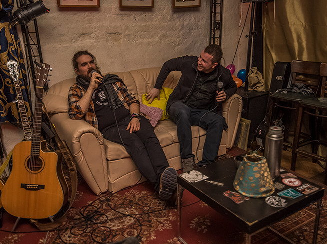 Zwei Künstler sitzen neben Gitarren auf einer Couch in der Kulturlounge Leipzig, Party, Tanzen, Clubs, Feiern.