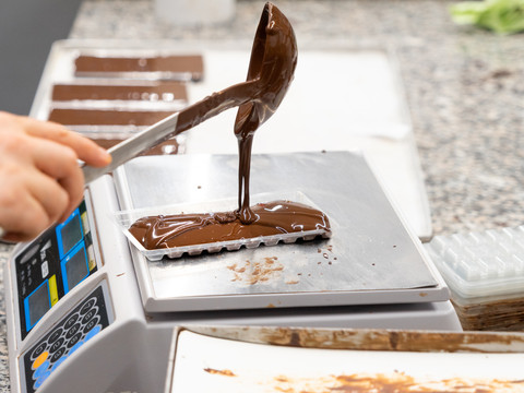 Auf einer Waage wird eine Schokoladentafel der Chocolaterie Praetsch in Wermsdorf händsich gegossen und abgewogen, regionale Produkte