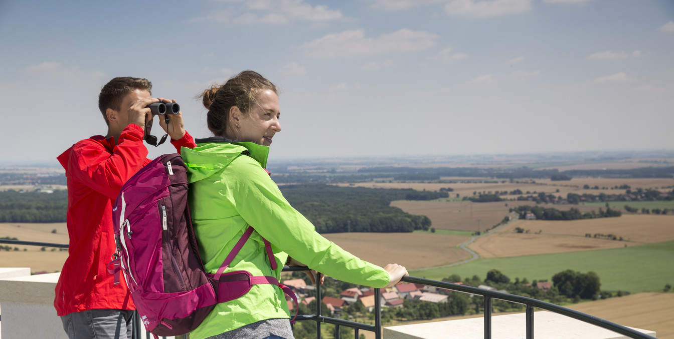 Seitenansicht eines Paares, das vom Albertturm in Collm in Wermsdorf schaut, er schaut mit dem Fernglas, Felder, Wälder, blauer Himmel