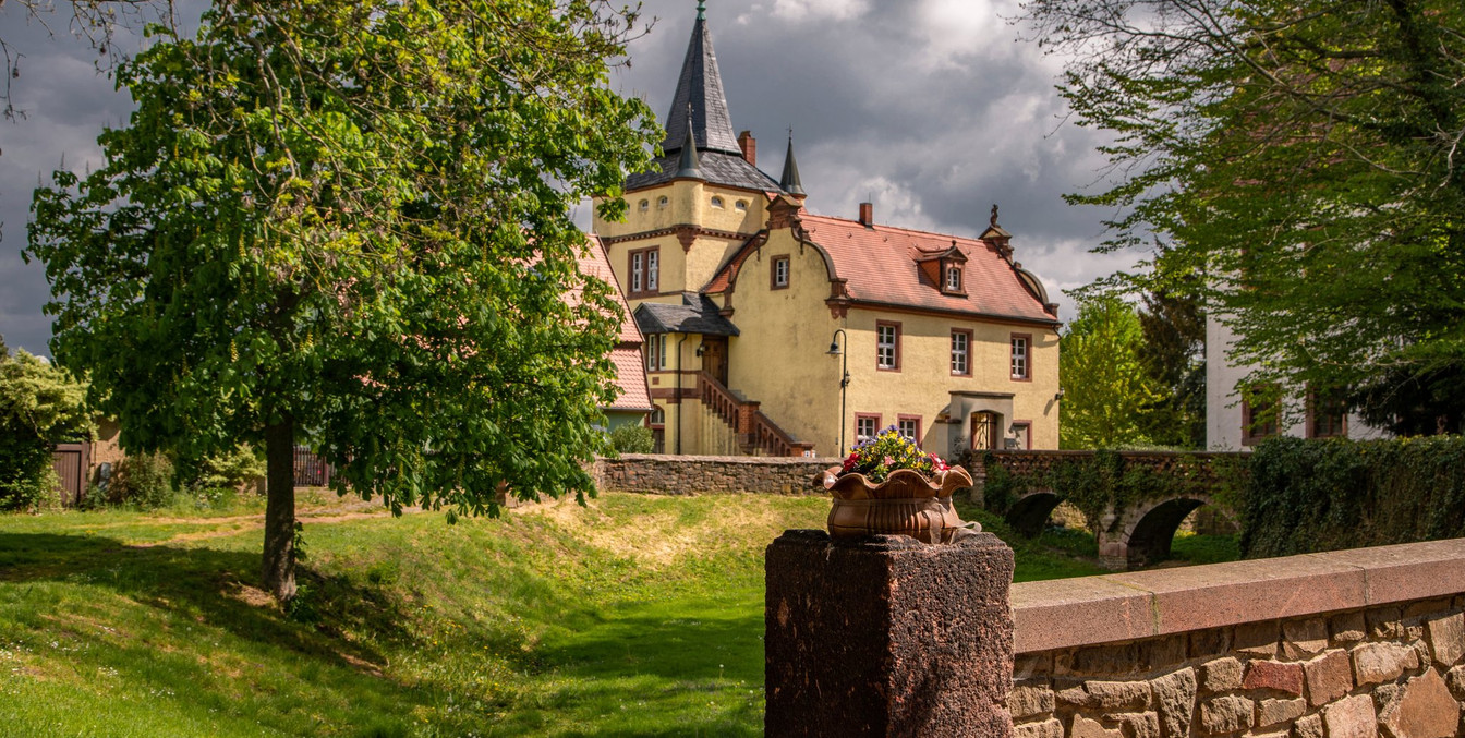 Blick auf die begrünte Anlage am Wasserschloss Podelwitz