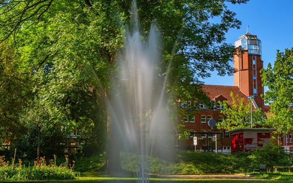 Wasserfontäne im Stadtpark Zeven mit Rathaus im Hintergrund