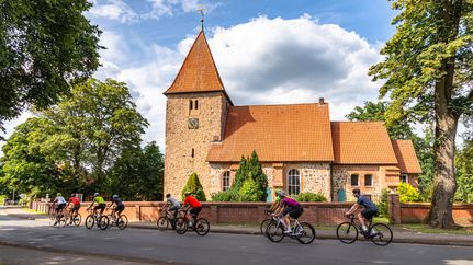 Rennradgruppe vor der St. Bartholomäus-Kirche in Kirchwalsede
