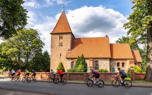 Rennradgruppe vor der St. Bartholomäus-Kirche in Kirchwalsede