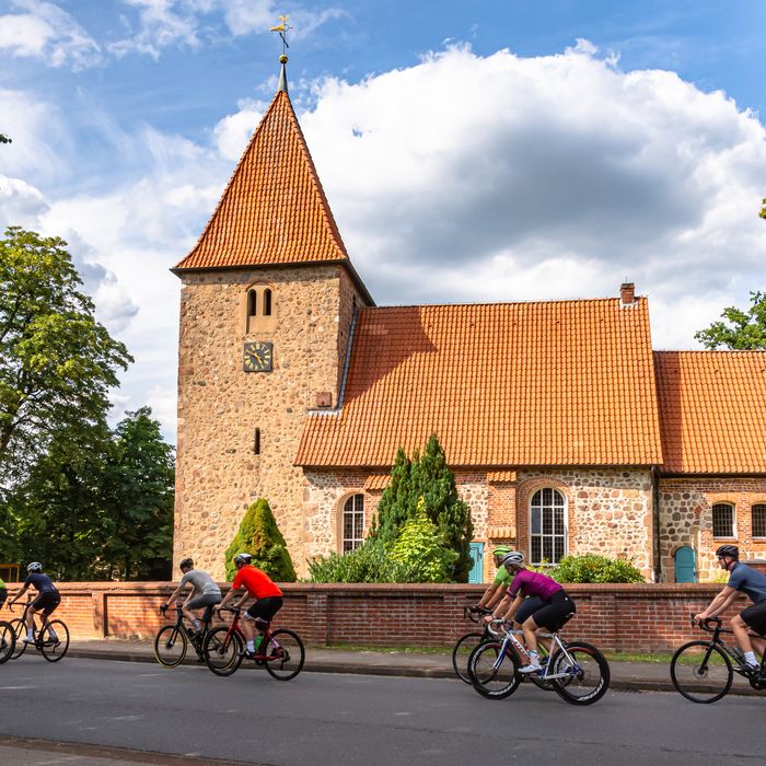 Rennradgruppe vor der St. Bartholomäus-Kirche in Kirchwalsede