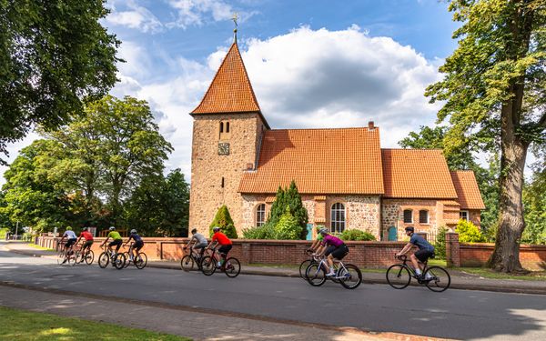 Rennradgruppe vor der St. Bartholomäus-Kirche in Kirchwalsede