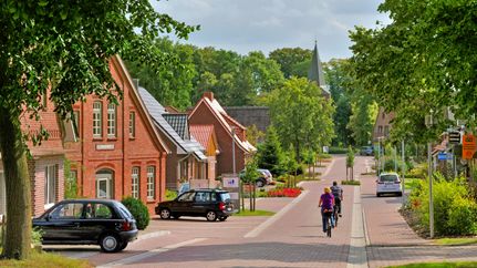 Radfahrer fahren in Richtung der Gangolf-Kirche in Oerel