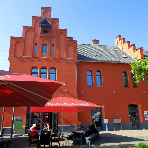 rotes Haus des "Wanderbahnhofs" Schladern mit Tourist-Info und Biergarten davor