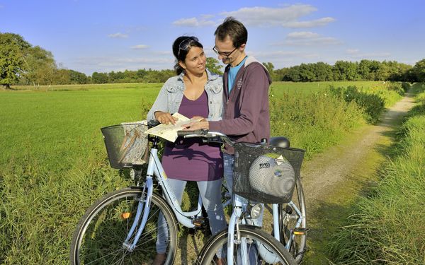 Radfahrer orientieren sich mithilfe einer Karte auf einem Feldweg