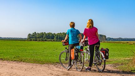Zwei Radfahrerinnen genießen bei einer Pause die weite Aussicht