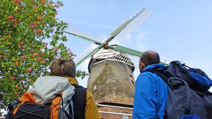 Wanderer schauen auf zu den Flügeln der Windmühle "Henriette"