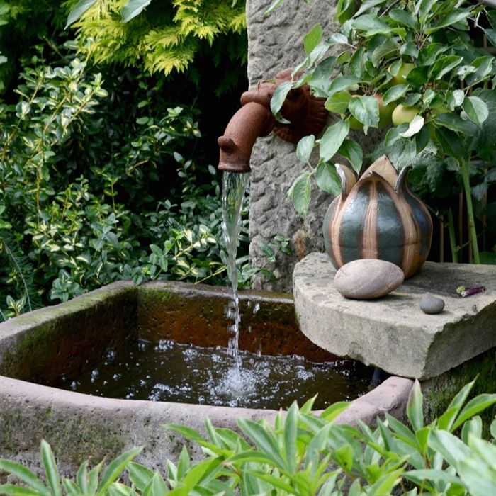 Ein dekorativer Brunnen plätschert im Garten Schönfeld