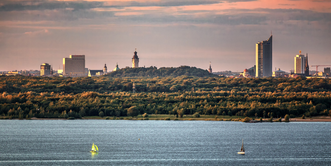 Die Skyline von Leipzig bei Sonnenuntergang ragt hinter dem Cospudener See auf, Freizeit, Wasser, Leipziger Neuseenland