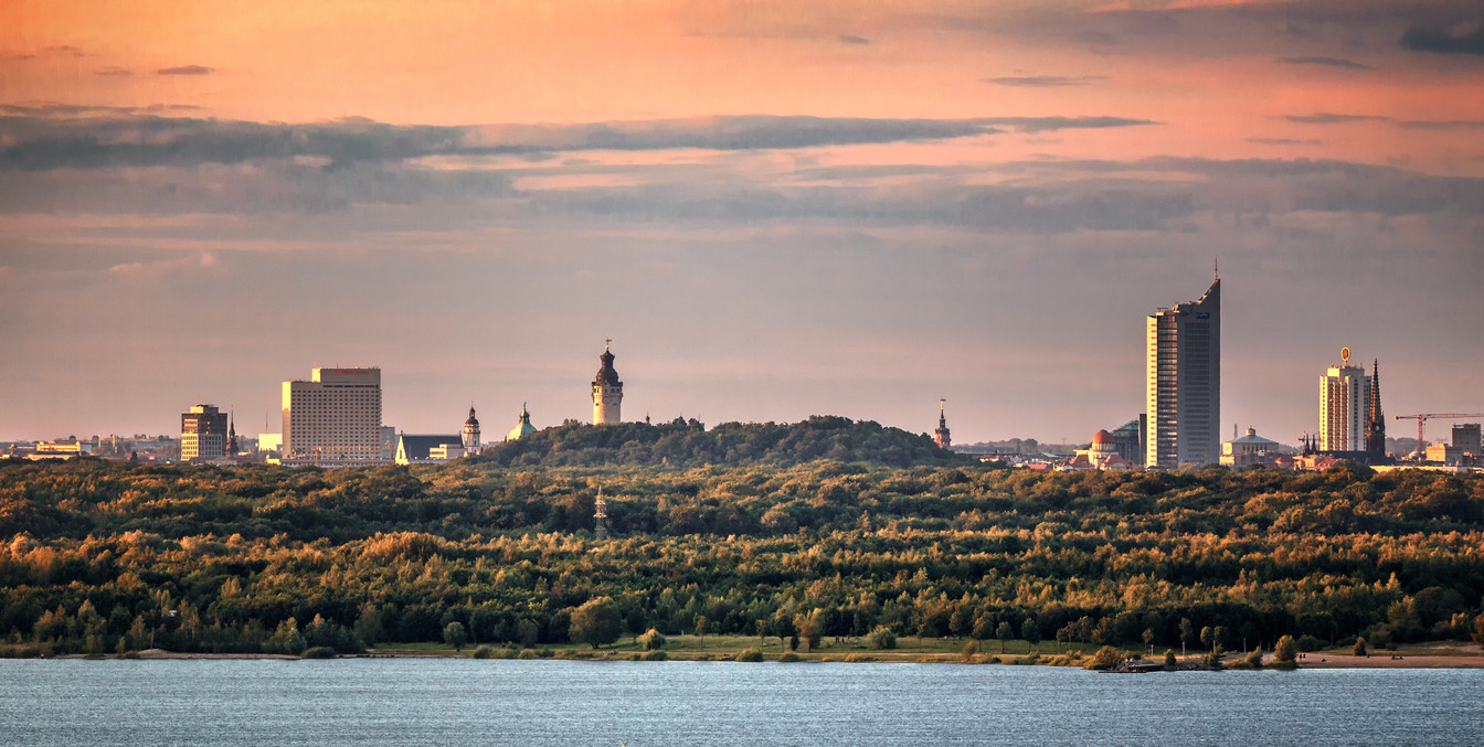 Die Skyline von Leipzig bei Sonnenuntergang ragt hinter dem Cospudener See auf, Freizeit, Wasser, Leipziger Neuseenland