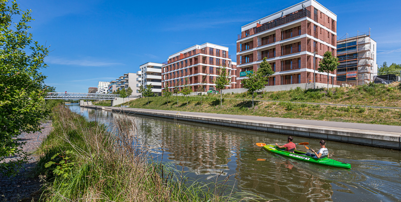 Zwei Kanufahrer befahren den Lindenauer Hafen, der von modernen Neubauten gesäumt ist, Wasserwege in Leipzig, Grünes Leipzig, Bootstouren, Freizeit