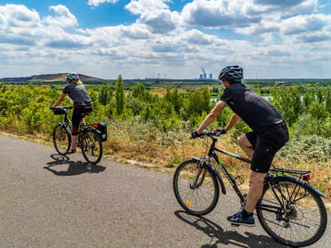 Zwei Fahrradfahrer machen eine Tour auf dem asphaltierten Rundweg um den Störmthaler See, im Hintergrund Natur und der Bergbau-Technik-Park, Sport, Aktiv, Fahrradfahren, Region, Leipziger Neuseenland 