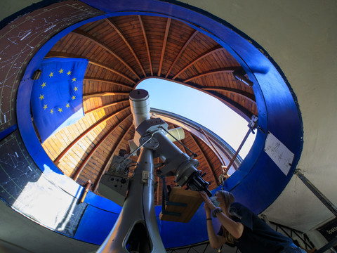 Blick ins Innere des Observatoriums, an dem eine junge Frau durch das Teleskop in den Himmel schaut, Wissenschaft, Observatorium, Sternwarte, Freizeit