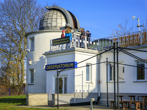 Blick von außen auf das Planetarium Schkeuditz, auf dessen Dach einer Gruppe junger Menschen die Funktionsweise des Teleskops erklärt wird, Freizeit, Wissenschaft, Leipzig für Gruppen