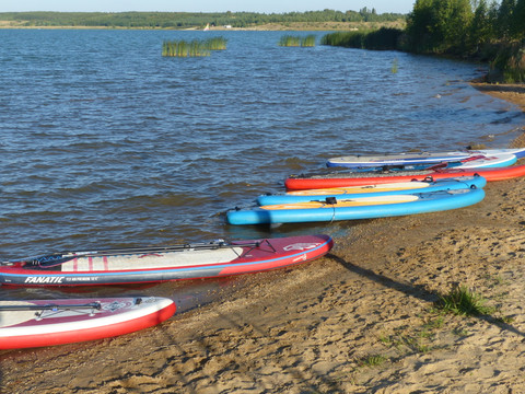 Stand-Up-Paddle-Boards liegen am Sandstrand eines Sees bereit, Leipziger Neuseenland, Aktiv, Wassersport