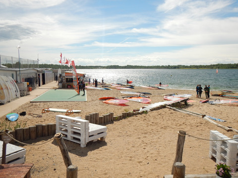 Am Strandufer des Schladitzer Sees stehen Sportler, die Windsurfen auf dem See ausprobieren wollen