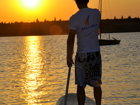 Ein junger Stand Up Paddler ist auf dem Schladitzer See bei Sonnenuntergang