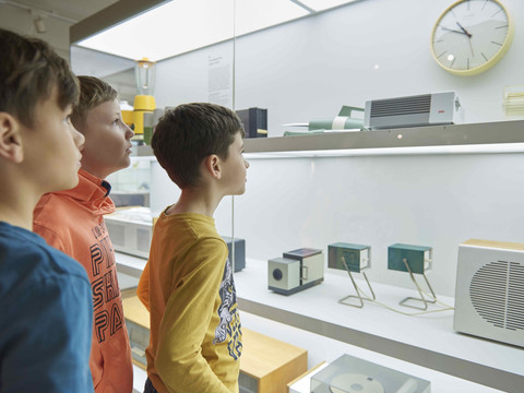 Kinder bestaunen die Exponate in einer beleuchteten Glasvitrine im GRASSI Museum für Angewandte Kunst.