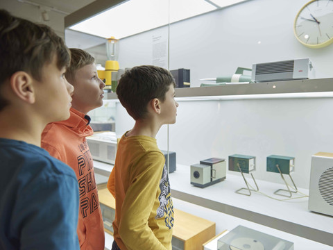 Kinder bestaunen die Exponate in einer beleuchteten Glasvitrine im GRASSI Museum für Angewandte Kunst.