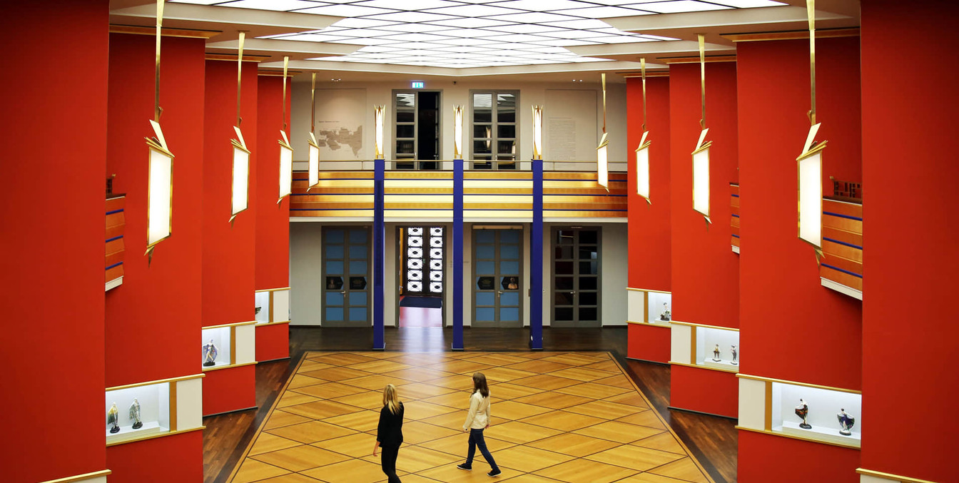 Blick von oben in den Ausstellungsraum Pfeilerhalle mit roten Säulen des Grassi Museums für Angewandte Kunst.