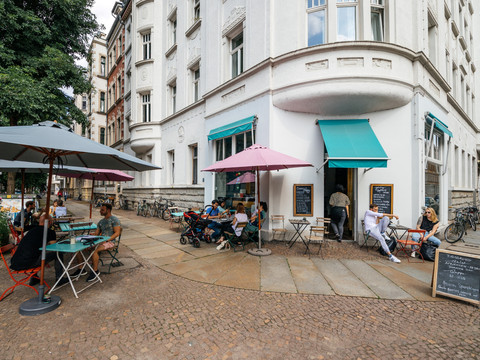 Außenbereich des Jimmy Orpheus mit Blick auf den Eingang zum Café, farbliche Markise, Sitzbereich und den angrenzenden Straßenzug, restaurant, kulinarik