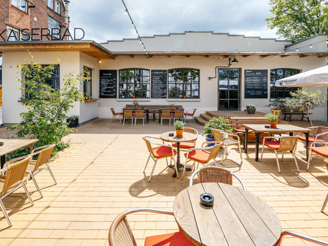 Fotografie des Außenbereiches des Kaiserbads im Leipziger Westen bei Sonnenschein; Sitzbereich, eingedeckte Cafétische, Gastronomie, freisitz
