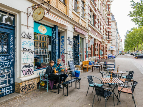 Blick auf den Außenbereich sowie die Fassade des Kartoffelfräulein; junge Gäste sitzen an den Tischen; Fassade mit Graffiti, Karl-Heine-Straße, Plagwitz, gastronomie, kulinarik
