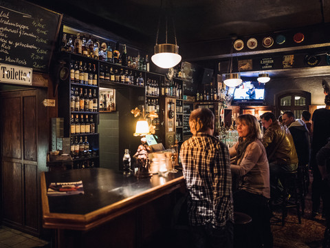 Das Geschehen im Pub, Gäste sitzen an der Bar und unterhalten sich in gemütlichem Ambiente, kneipe, pub, gastonomie