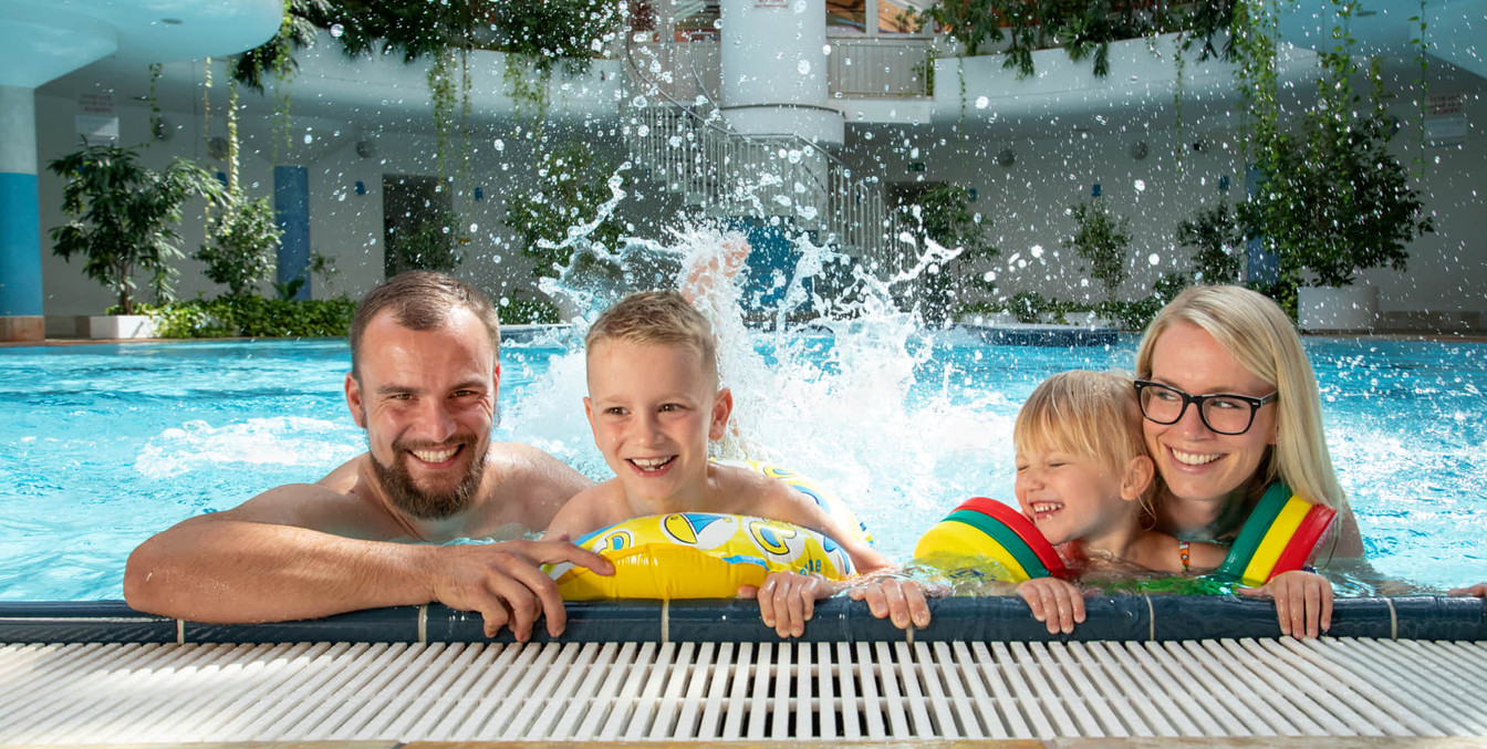 Eine Familie mit 2 Kindern plantscht am Beckenrand des RIFF's, Schwimmbad-Leipzig-mit-Kindern-Freizeit