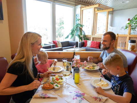 Eine Familie sitzt gemeinsam an einem Tisch im Restaurant des Freizeitbades Riff in Bad Lausick und isst Mittag