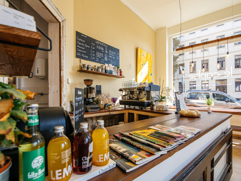 Aufnahme des hellen und moderne Cafés le caphe mit Blick auf die Bar und alle zugehörigen Utensilien sowie das große Fenster zur Straße (im Hintergrund), cafe, restaurant