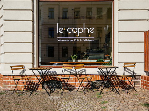 Blick auf den Freisitz (Stühle und Tische) vor dem le caphe sowie die Aufschrift der Ladenbezeichnung auf dem großen Fenster, gastronomie, cafe, freizeit
