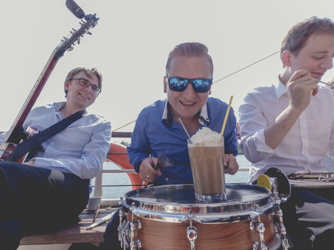 Eine Musikband sitzt auf der MS Santa Babara auf dem Zwenkauer See bei bester Laune und Sonnenschein