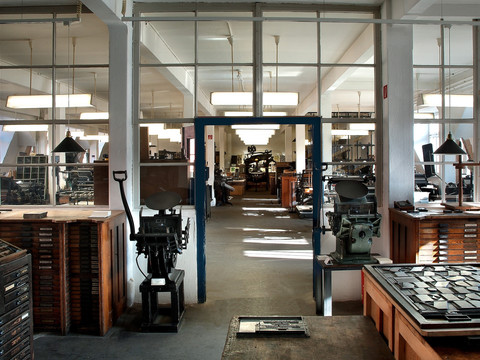 Blick in den Raum des Museums für Druckkunst mit vielen Materialien und historischen Druckmaschinen für künstlerische Druckverfahren.