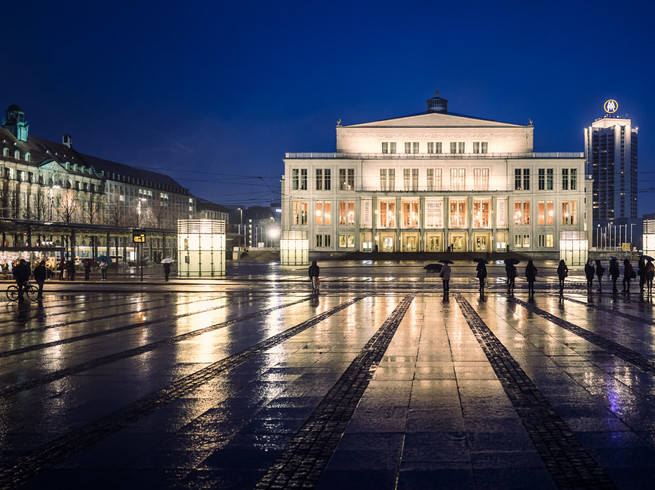 Blick auf die beleuchtete Oper Leipzig mit Spiegelungen der Lichter auf dem nassen Boden des Augustusplatz die eine wahre Sehenswürdigkeit der Musikstadt Leipzig ist, Kultureinrichtung, Veranstaltungen